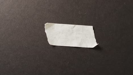 Video-of-close-up-of-white-paper-tape-piece-on-black-background