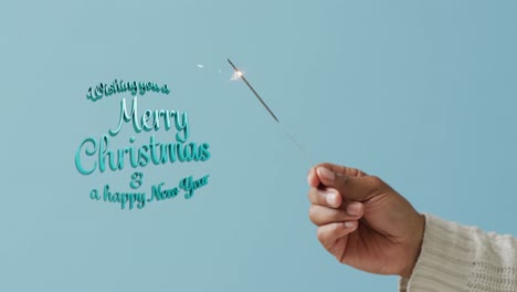Animation-of-christmas-greetings-text-over-man's-hand-holding-sparkler