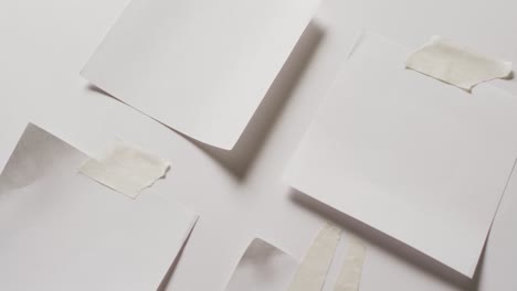 Video-of-close-up-of-four-white-memo-notes-with-copy-space-taped-to-white-background