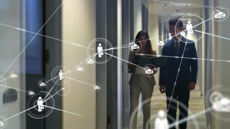 Animation-of-network-of-icons-over-diverse-businessman-and-businesswoman-discussing-at-office
