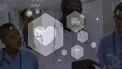 Animation-Medizinischer-Symbole-über-Einem-Team-Verschiedener-Ärzte-Und-Gesundheitspersonal,-Die-Im-Krankenhaus-Diskutieren