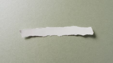 Video-of-close-up-of-torn-piece-of-white-paper-on-green-background