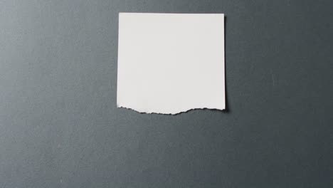 Video-of-close-up-of-torn-piece-of-white-paper-on-black-background