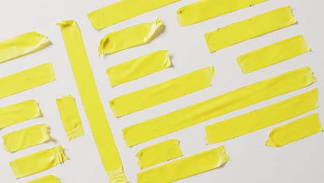Video-of-close-up-of-multiple-yellow-tapes-pieces-on-white-background