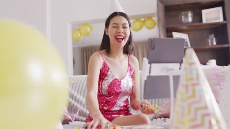 Video-Einer-Lächelnden-Gemischtrassigen-Frau,-Die-Konfetti-Mit-Partyhut-Wirft-Und-Ein-Rosa-Kleid-Trägt