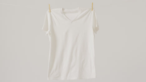 Video-of-close-up-of-white-t-shirt-hanging-on-white-background
