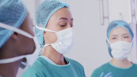 Video-of-biracial-female-surgeon-talking-with-diverse-colleagues-during-operation-in-theatre