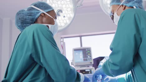 Low-Angle-Video-Von-Zwei-Unterschiedlichen-Weiblichen-Chirurgen,-Die-Sich-Während-Der-Operation-Im-Operationssaal-Unterhalten