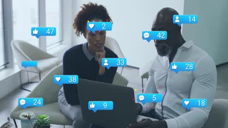 Animation-of-multiple-social-media-icons-against-african-american-man-and-woman-discussing-at-office