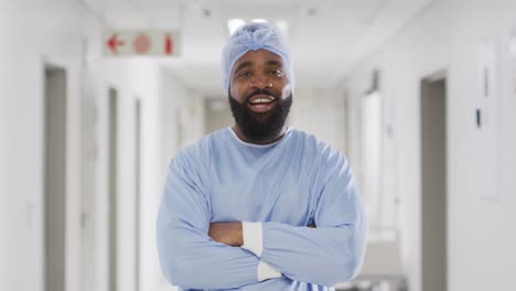 Video-portrait-of-smiling-african-american-male-doctor-in-surgical-cap-and-gown,-copy-space