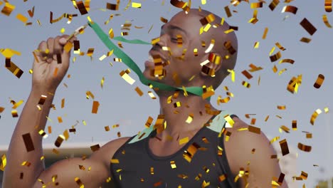 Animation-of-gold-confetti-falling-over-african-american-man-holding-gold-medal