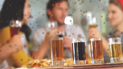 Animation-of-dark-spots-against-close-up-of-four-shot-glasses-on-bar-table