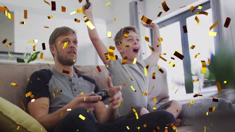 Animation-of-gold-confetti-falling-over-caucasian-man-with-son-cheering-playing-video-games
