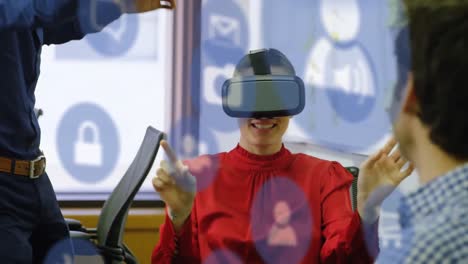 Animation-Digitaler-Symbole-Und-Datenverarbeitung-über-Einer-Kaukasischen-Frau,-Die-Im-Büro-Ein-VR-Headset-Trägt