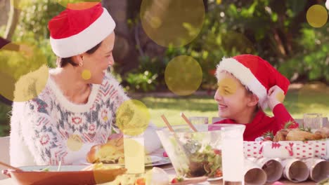 Animation-of-yellow-spots-over-caucasian-family-in-santa-hats-at-christmas-table