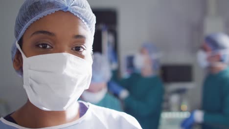 Video-portrait-of-african-american-female-surgeon-in-face-mask-in-operating-theatre,-with-copy-space
