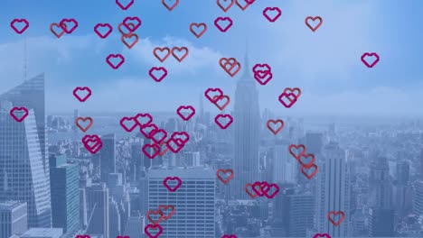 Animation-of-multiple-red-heart-icons-floating-over-aerial-view-of-cityscape