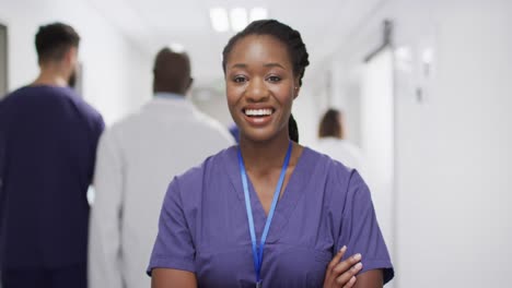 Retrato-En-Video-De-Una-Doctora-Afroamericana-Sonriendo-En-El-Concurrido-Pasillo-Del-Hospital,-Espacio-Para-Copiar
