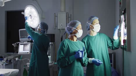 Video-Von-Zwei-Verschiedenen-Weiblichen-Chirurgen,-Die-über-Röntgenaufnahmen-Auf-Einem-Leuchtkasten-Im-Operationssaal-Diskutieren,-Kopierraum