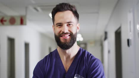 Video-portrait-of-smiling,-bearded-caucasian-male-medical-worker-in-corridor,-copy-space