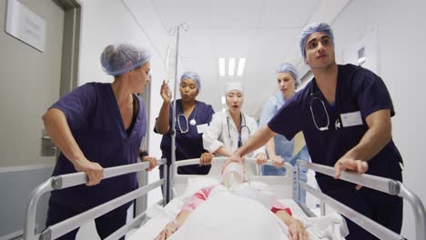 Video-De-Un-Grupo-Diverso-De-Trabajadores-Médicos-Moviendo-Al-Paciente-Con-Un-Ventilador-Y-Goteando-Por-El-Pasillo-De-La-Cama