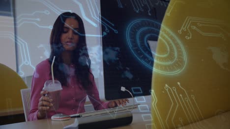 Animation-of-microprocessor-connections-over-biracial-woman-with-smoothie-using-computer-at-office
