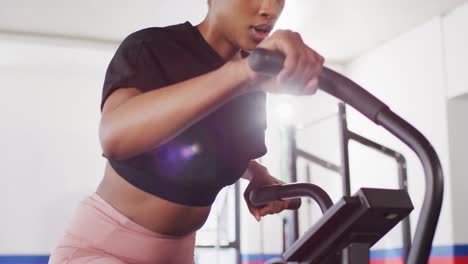 Video-of-confident-african-american-woman-on-exercise-bike-working-out-at-a-gym