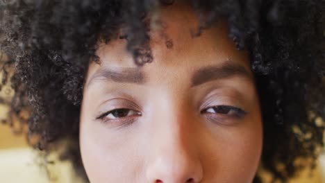 Video-close-up-portrait-of-the-opening-and-smiling-eyes-of-biracial-woman-with-afro