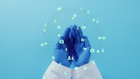 Animation-of-network-of-connections-with-icons-over-hands-holding-blue-ribbon-on-blue-background