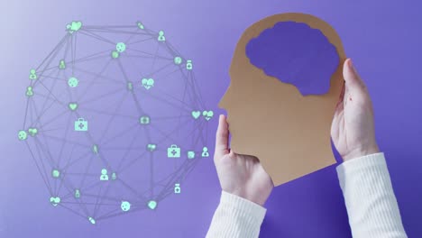 Animation-of-globe-of-connections-with-icons-over-hands-holding-human-head-on-purple-background