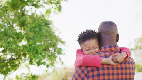 Happy-african-american-father-and-his-son-embracing-in-garden