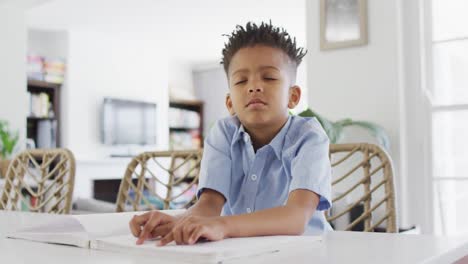 Glücklicher-Afroamerikanischer-Junge,-Der-Am-Tisch-Sitzt-Und-Blindenschrift-Liest