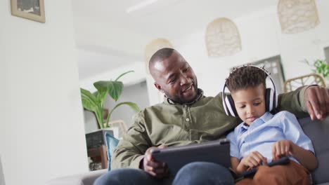 Glücklicher-Afroamerikanischer-Mann-Und-Sein-Sohn-Sitzen-Auf-Dem-Sofa-Und-Benutzen-Ein-Tablet