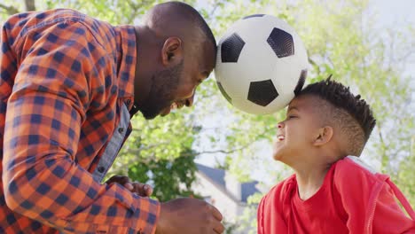 Glücklicher-Afroamerikanischer-Vater-Und-Sein-Sohn-Spielen-Fußball-Im-Garten