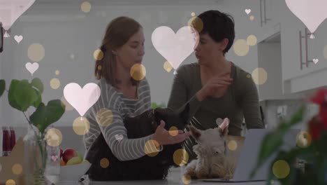 Animation-of-hearts-over-caucasian-female-couple-with-their-pet-dogs