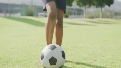 Video-of-african-american-schoolboy-playing-football-barefoot-in-field