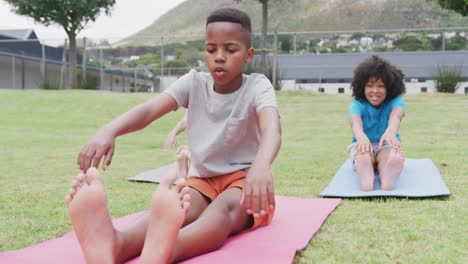 Video-of-diverse-schoolboy-and-schoolgirls-practicing-yoga-stretches-in-outdoor-class,-copy-space