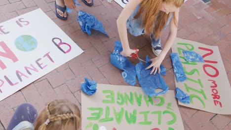 Video-of-diverse-schoolchildren-making-protest-placards-in-schoolyard,-copy-space