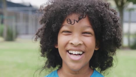 Video-portrait-of-smiling-biracial-schoolgirl-in-school-playing-field,-with-copy-space