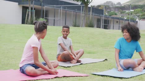 Video-of-diverse,-happy-schoolgirls-and-schoolboy-talking-during-outdoor-yoga-class,-copy-space
