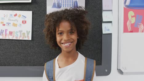 Video-portrait-of-happy-african-american-schoolboy-smiling-in-school-classroom