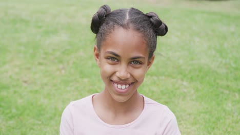 Video-portrait-of-smiling-biracial-schoolgirl-in-school-playing-field,-with-copy-space