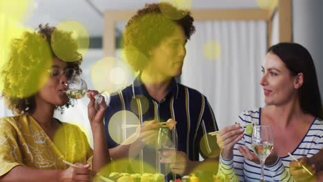 Animation-of-yellow-spot-lights-over-diverse-friends-having-sushi-and-drink