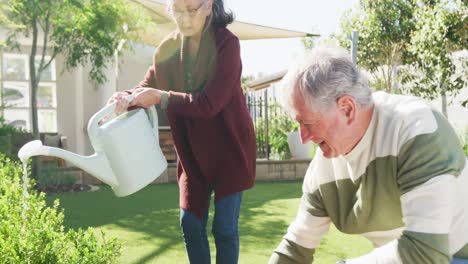 Happy-diverse-senior-couple-working-in-garden-on-sunny-day