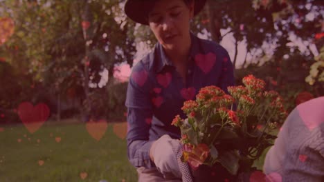 Animation-of-heart-emojis-over-caucasian-woman-gardening