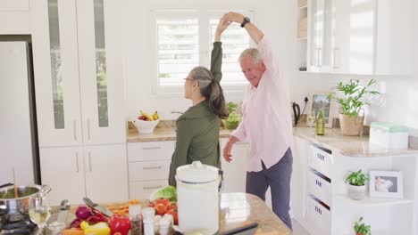 Glückliches,-Vielfältiges-älteres-Paar,-Das-Händchen-Hält-Und-In-Der-Küche-Tanzt