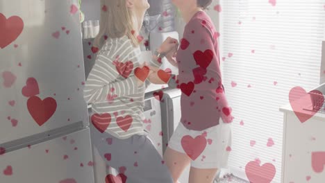 Animation-of-heart-emojis-over-happy-caucasian-female-couple-in-love-dancing