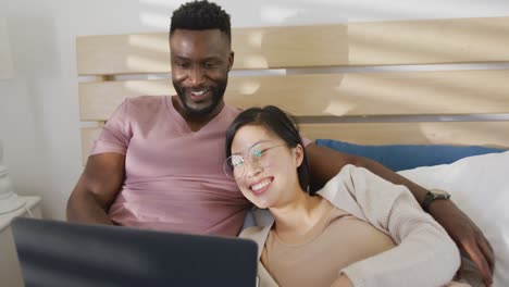Glückliches,-Vielfältiges-Paar,-Das-Laptop-Benutzt-Und-Im-Schlafzimmer-Liegt