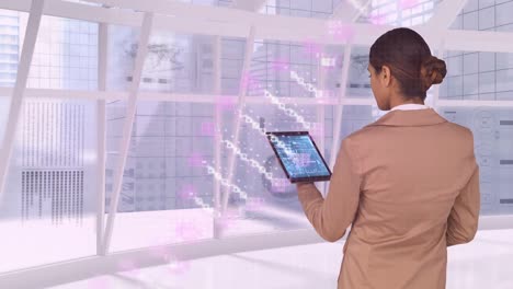 Animation-of-dna-strand-spinning-over-biracial-businesswoman-using-tablet-in-office