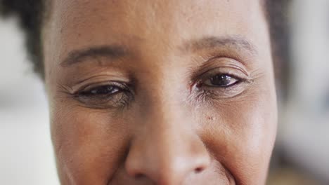 Video-close-up-portrait-of-opening-eyes-of-happy-african-american-woman-smiling-at-home,-copy-space
